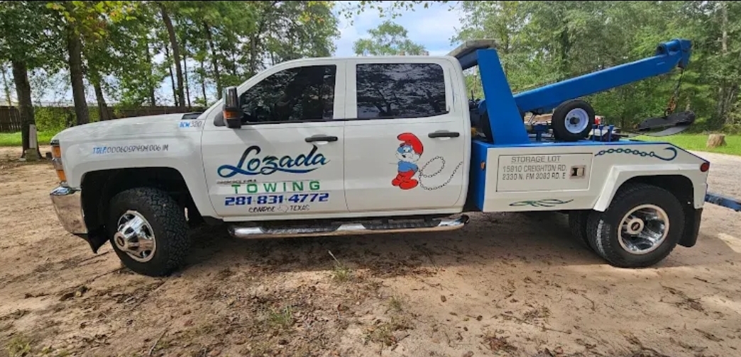 Flatbed tow truck parked by the trees